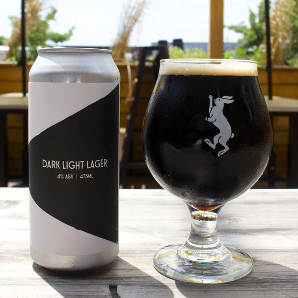 Can of Mascot's dark light lager next to a chilled glass full of the beer.